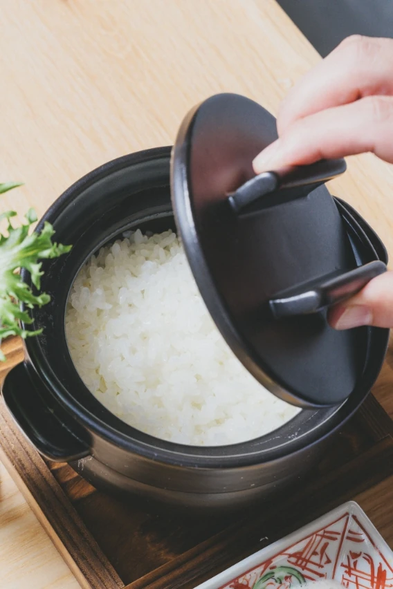 炊きたての白ご飯が入った土鍋の蓋を開ける様子