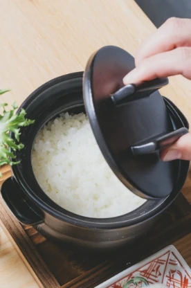 炊きたての白ご飯が入った土鍋の蓋を開ける様子